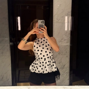 Haut péplum à pois pour femme porté avec un short noir et un sac à bandoulière