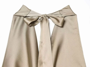 Detailed close-up of champagne satin fabric with elegant halter tie and silky texture
