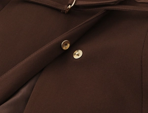 Detail of dark brown twill vest featuring premium golden metal snap buttons and neat stitching