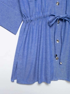 Dettaglio della coulisse in vita e bottoni lucidi su una camicia blu strutturata