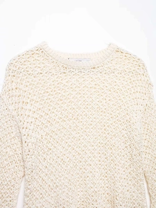 Detail of cream crochet knit sweater showing openwork texture and ribbed crew neck