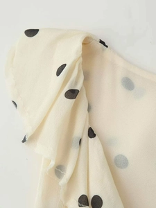 Détail du tissu en mousseline à grands pois noirs avec finitions à volants