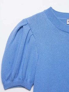 Détail du cardigan bleu en maille avec col rond et texture de manches bouffantes plissées
