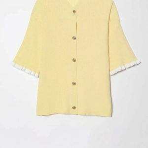Women's yellow knit cardigan with V-neck, gold buttons and white ruffled sleeve details