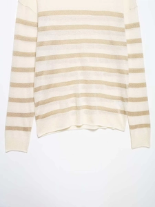 Close-up of off-white knit sweater showing metallic gold striped texture and crew neck
