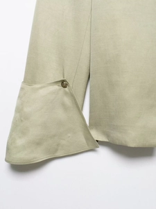Close-up of vintage blazer cuff in sage green fabric with embossed gold button detail