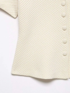 Gros plan sur la maille gaufrée beige montrant la texture et les boutons assortis