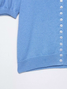 Détail du cardigan en maille bleu clair avec manches bouffantes et boutons en perle
