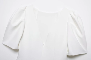 Detail of white crepe puff sleeve top with V-neckline and hidden zipper closure