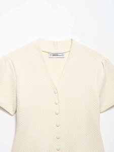Gros plan du cardigan en maille col V avec manches bouffantes et tissu texturé crème