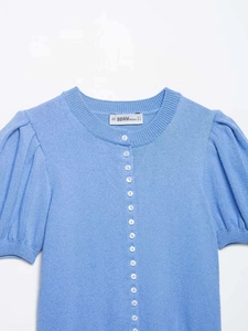 Détail du cardigan en tricot bleu avec boutons ronds blancs et col rond côtelé