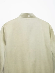 Detail of light green blazer back seam showing fine linen fabric texture and tailoring