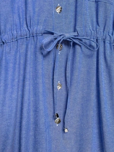 Dettaglio della camicia blu con coulisse regolabile in vita e punte in metallo