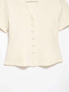 Détail du cardigan en maille crème avec col en V et texture gaufrée élégante