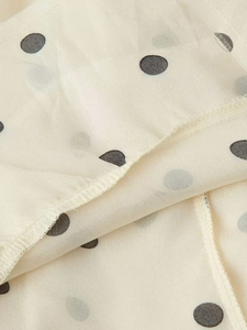 Détail macro du tissu beige à pois avec coutures de qualité et texture délicate