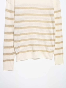 Close-up of fine knit texture with metallic gold stripes on cream-colored fabric