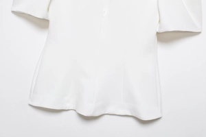 Detail of the white bubble sleeve top showing the invisible zipper and fitted waist cut