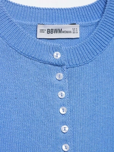 Vue détaillée d'un gilet en maille bleu clair avec boutons blancs et côtes fines
