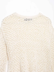 Detail view of the intricate beige open-knit geometric texture and ribbed neckline finish