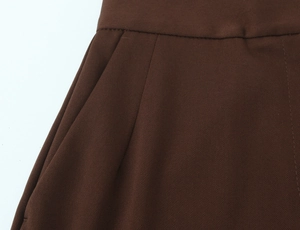 Detailed close-up of high-waisted dark brown trousers with side slant pockets