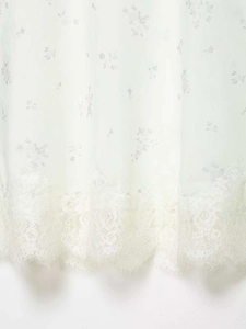 Detail view of white skirt featuring delicate floral patterns and eyelash lace trimming