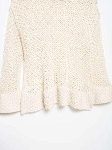 Detail of off-white crochet knit top showing hollow diamond mesh and flared sleeves