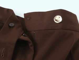 Detailed close-up of dark brown twill fabric with silver metal button and precise stitching