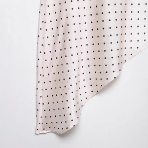 Détail du tissu satiné à pois pour robe d'été asymétrique tendance en beige et noir