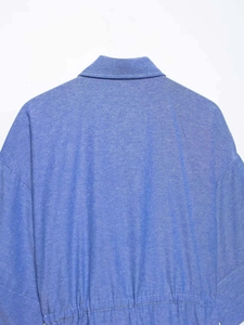 Dettaglio di camicia blu che mostra il colletto, la trama e la vita elastica arricciata