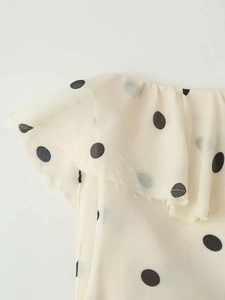 Détail du bord à volants sur la robe d'été asymétrique crème à pois noirs élégante