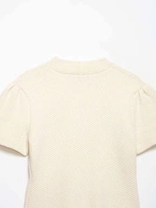 Détail du cardigan en maille crème avec texture gaufrée et manches bouffantes