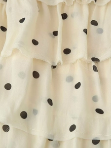Détail du tissu en mousseline crème à pois noirs avec des textures à volants superposés