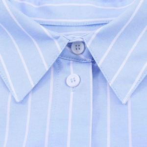 Close-up of the pointed collar and white buttons on a light blue striped cotton shirt