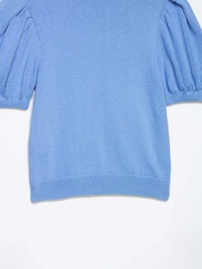 Détail du cardigan en maille bleu clair avec manches bouffantes et finitions côtelées