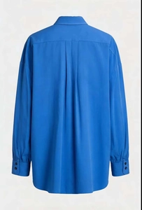 Macro detail of vibrant blue shirt back showing box pleat design and smooth fabric texture