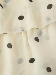 Gros plan du tissu en mousseline légère à pois noirs avec détails de volants superposés