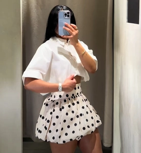 Détail de la chemise courte blanche et de la jupe bouffante à pois noirs pour femmes