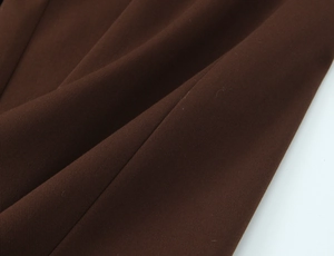 Detailed close-up of dark brown woven fabric showing the premium twill texture and drape