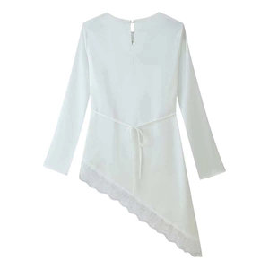 Dettaglio di maglia bianca a maniche lunghe con orlo asimmetrico e bordo in pizzo fine