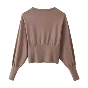 Detail of brown knitted long-sleeve top showing ribbed hem and puff sleeve cuffs from the back