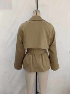 Detail view of the double-layer back storm flap and belted waist on khaki trench jacket
