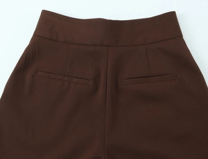 Detail of dark brown high-waisted trousers featuring back welt pockets and twill fabric