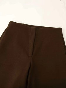 Detail of deep brown wool trousers showing the waistband texture and minimalist design