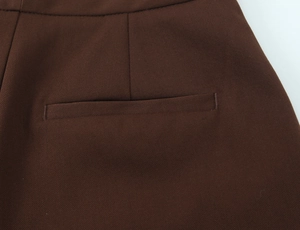 Close-up of pocket detailing on high-waisted dark brown trousers with twill texture