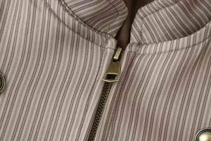 Détail d'une veste rayée vintage avec fermeture éclair en bronze et col montant ajusté