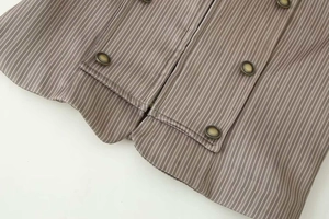 Détail du tissu à fines rayures avec boutons métalliques et fermeture éclair