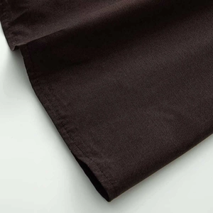 Close-up of the fine stitching and textured weave on the hem of a brown cotton dress