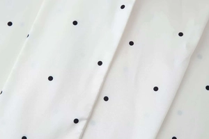 Close-up of white chiffon fabric with classic black polka dots on a summer blouse