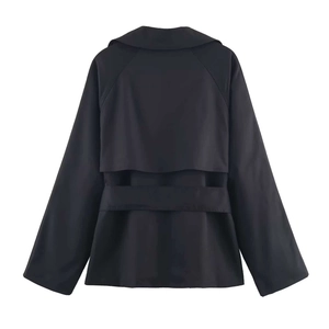 Detail view of the back of a black trench coat with waist belt and wind flap detail