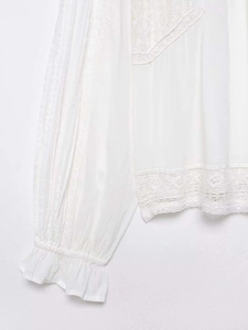 Detailansicht der weißen Bluse mit Spitze, Faltenärmeln und gerüschten Manschetten